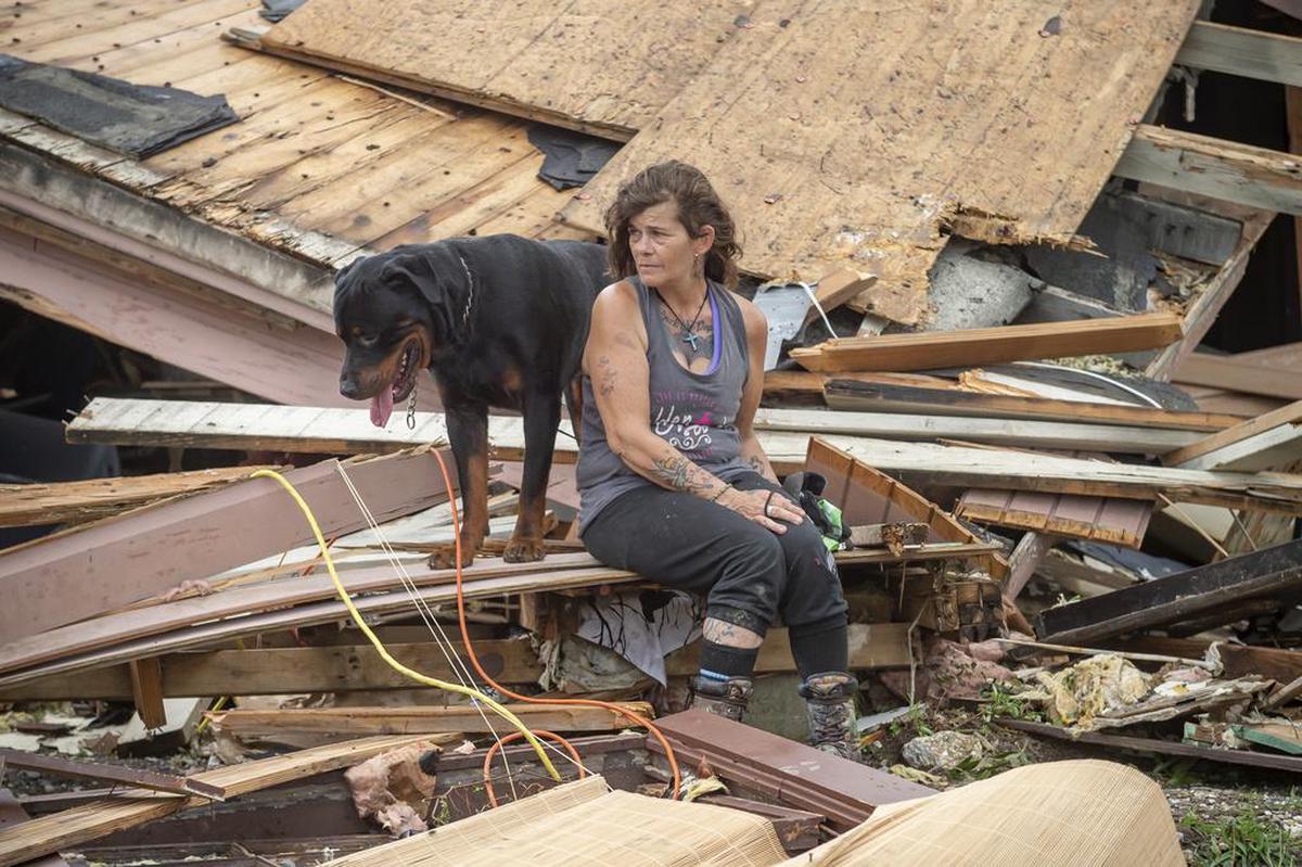 A woman and her dog sit in front of their home destroyed by Hurricane Ida in Homa, Luciana.