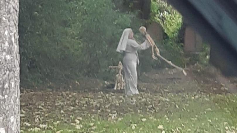 A nun dancing in the cemetery with a skeleton