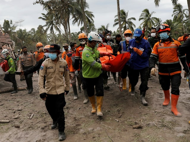 Rescue workers carry a body bag.