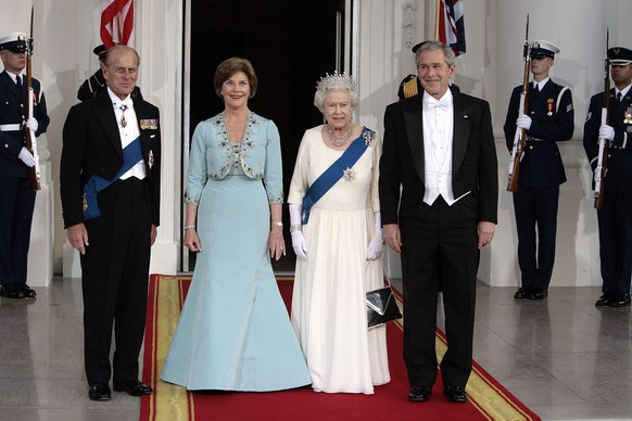 On formal occasions, the Queen often wears a white dress with gloves and a blue sash, as seen here when she met US President George W. Bush in 2007. 