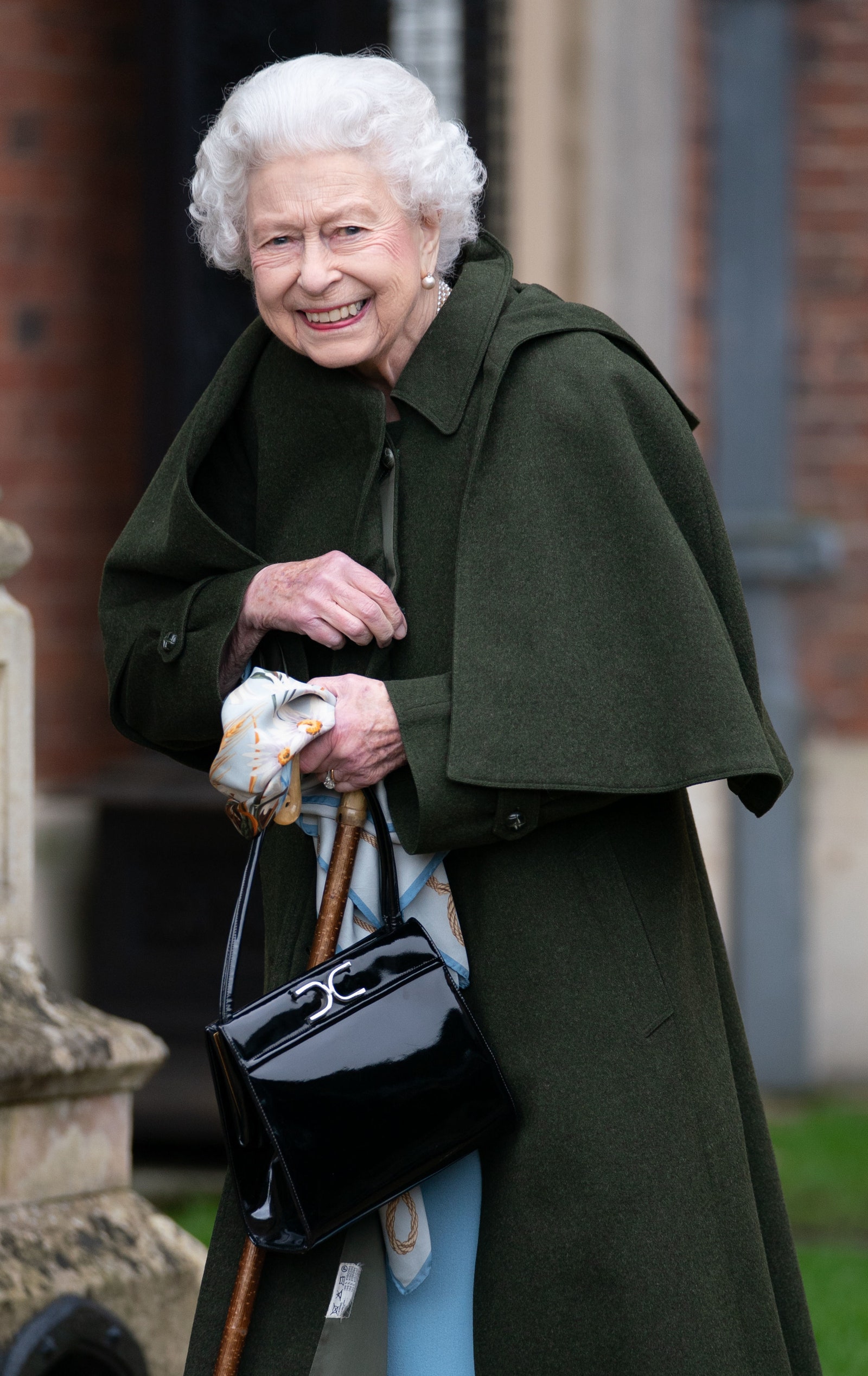 Queen Elizabeth II in a coat with a blue dress and a black bag