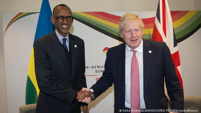 Rwandan President Paul Kagame and British Prime Minister Boris Johnson shake hands in front of the national flag at the 2020 Economic Summit in London