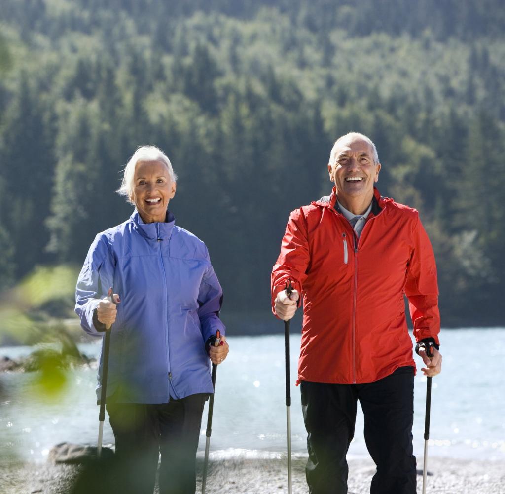 Two elderly people doing Nordic walking in nature