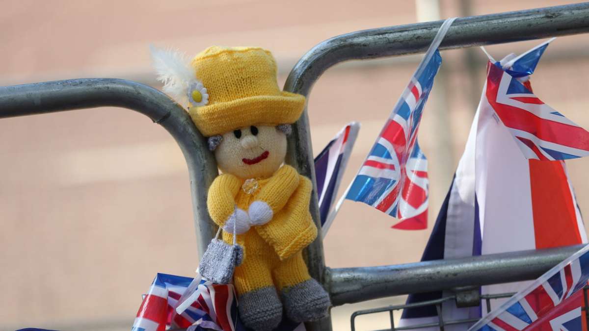 Eine Queen-Puppe und Flaggen sind zu Ehren der verstorbenen britischen Königin an Straßenabsperrung in London abgebracht.